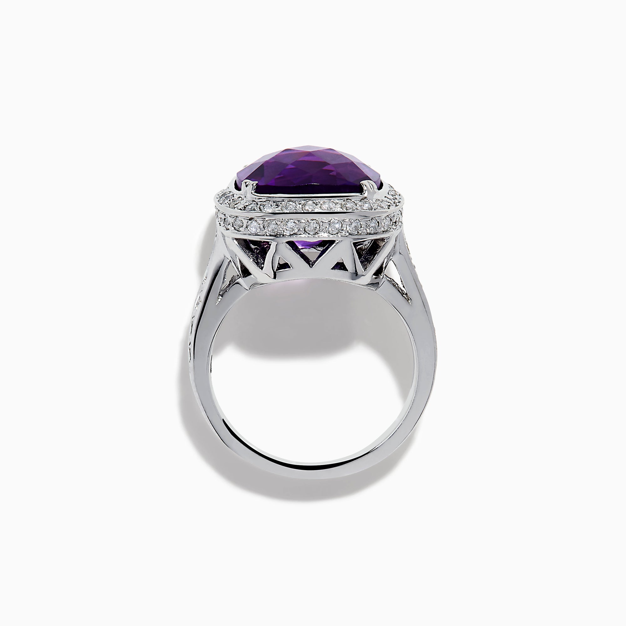 The 18K White Gold Amethyst and Diamond Cushion Halo Cocktail Ring features a striking cushion-cut amethyst center, a sparkling diamond halo, and clear stones on the band, elegantly displayed against a white background.