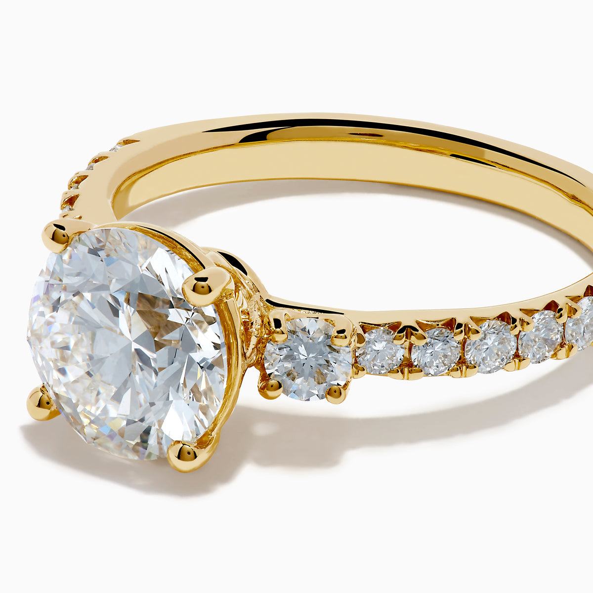 The Star Lab Grown Diamond Ring in 18K yellow gold features a large round center stone with smaller diamonds along the band, shown against a white background.