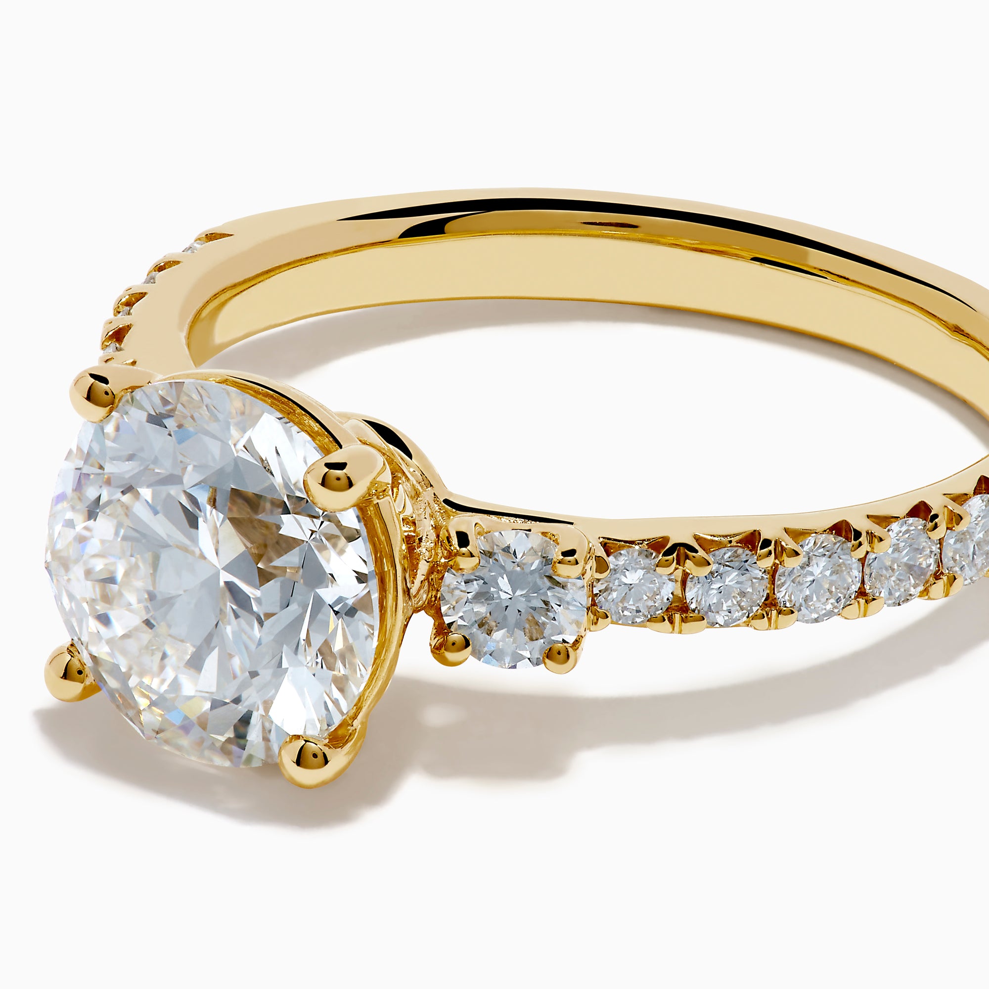The Star Lab Grown Diamond Ring in 18K yellow gold features a large round center stone with smaller diamonds along the band, shown against a white background.