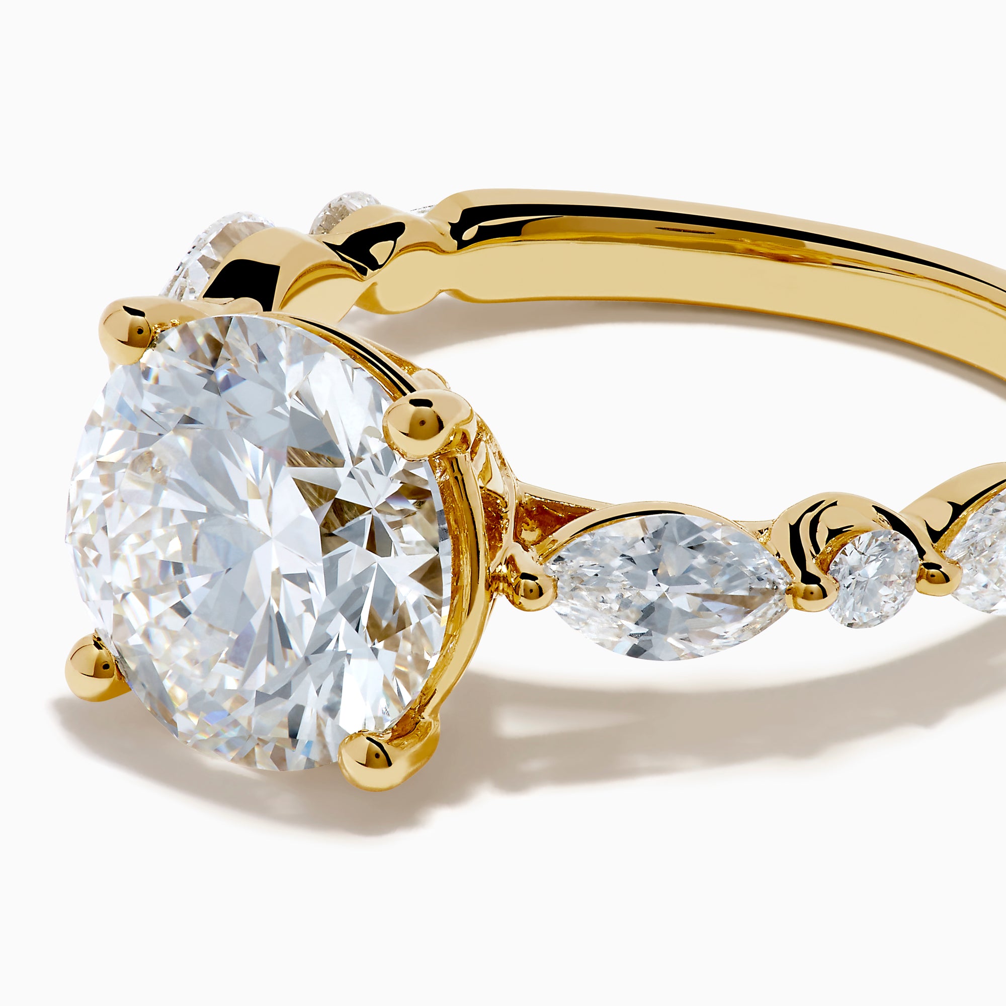 The Star Lab Grown Diamond Ring in 18K Yellow Gold features a large round lab diamond center, accented by three smaller diamonds on each side, all set against a white background.