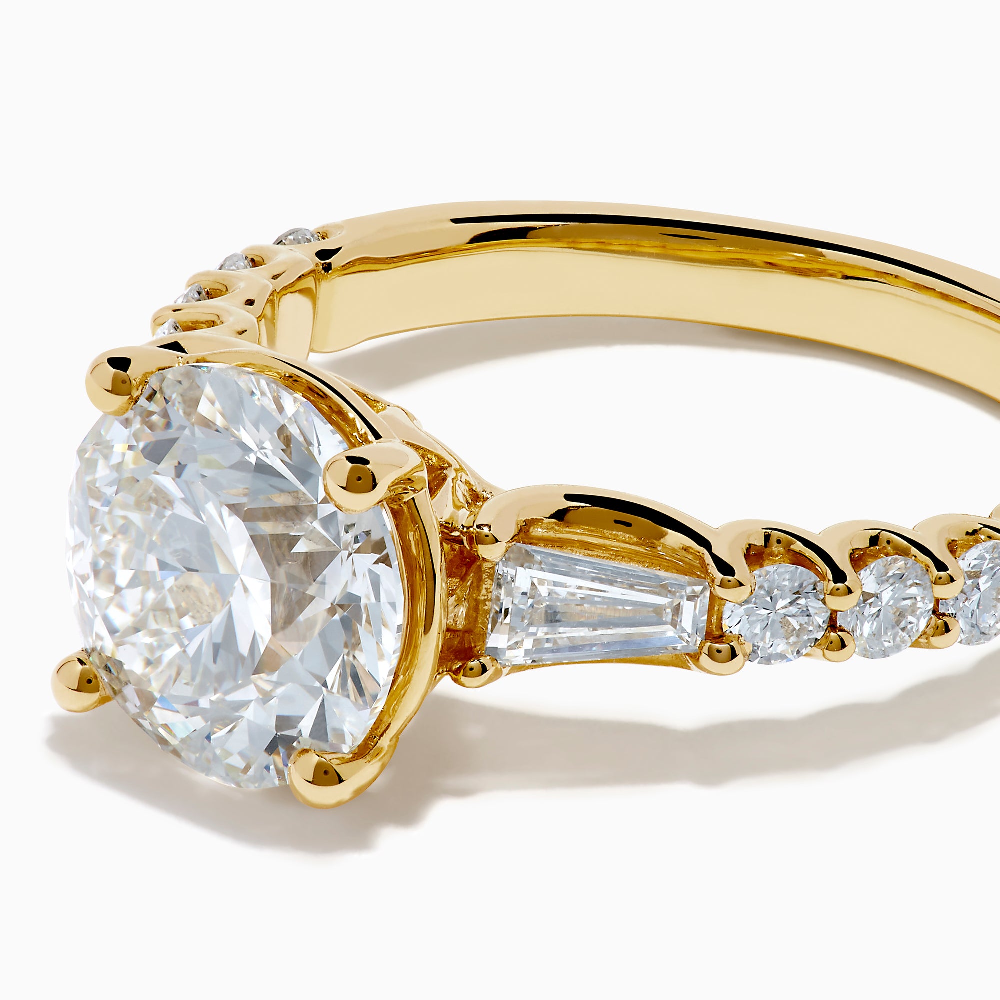 The Star Lab Grown Diamond Ring in 18K Yellow Gold showcases a large oval-cut lab diamond center stone with smaller rectangular accents along the band, elegantly displayed on a plain white background.