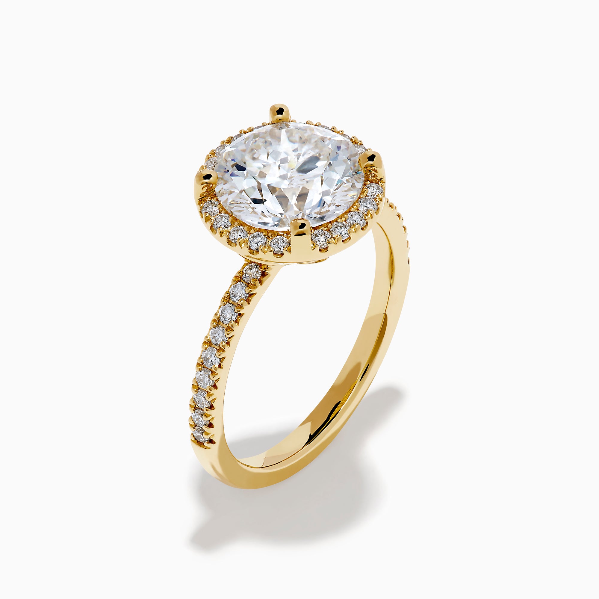The Star Lab Grown Diamond Halo Ring in 18K Yellow Gold showcases a large oval lab diamond center, encircled by a halo of star lab diamonds and additional diamonds along the band for extra brilliance.