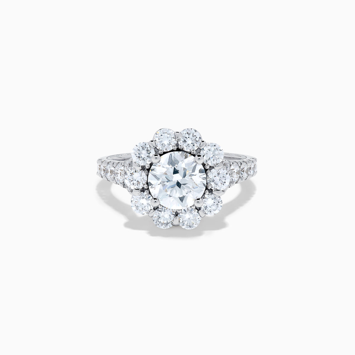 The Star Lab Grown Diamond Fleur Ring in 18K White Gold showcases a large round center lab diamond, with a sparkling halo of smaller diamonds and extra diamonds set along the band.