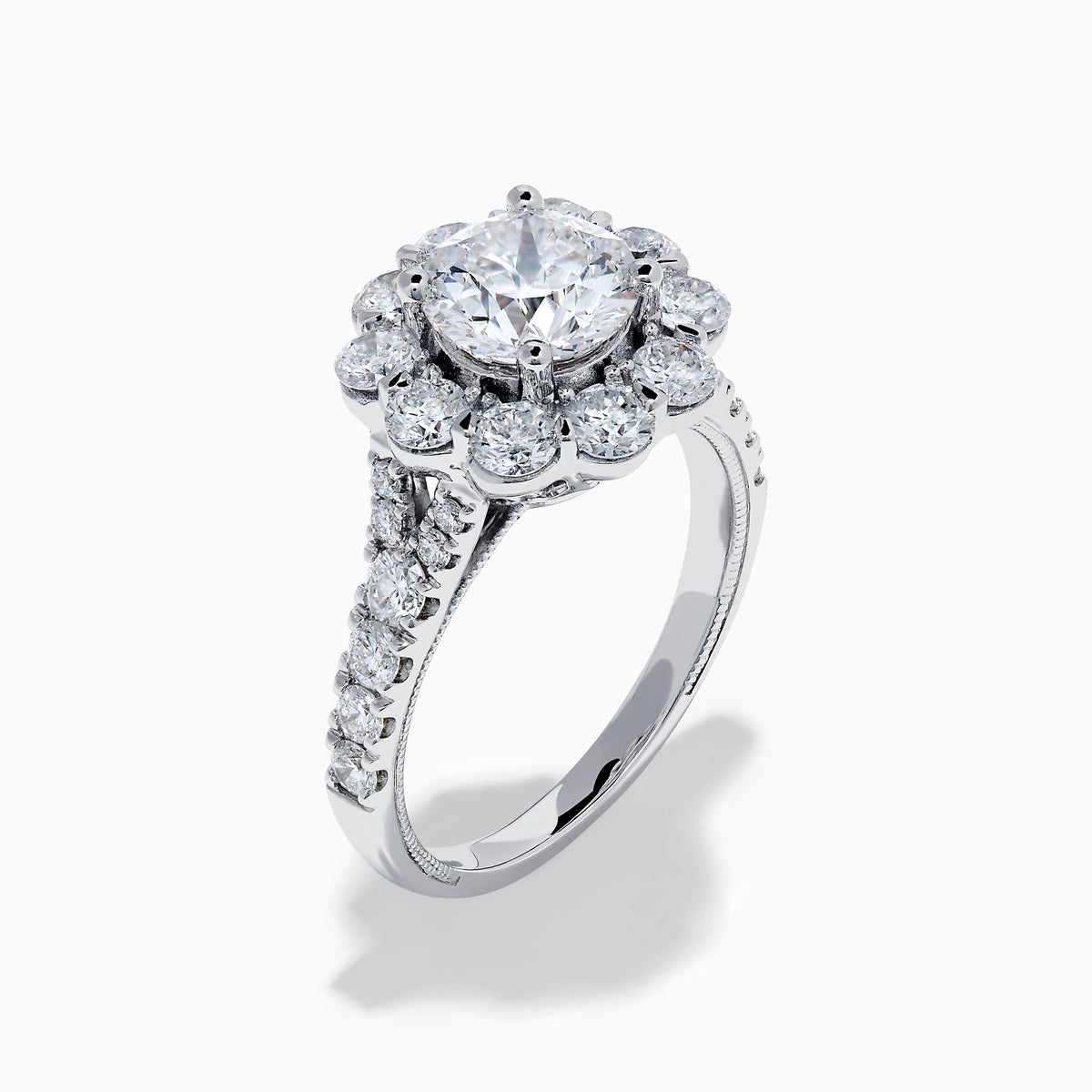 The Star Lab Grown Diamond Fleur Ring in 18K White Gold showcases a large round center lab diamond, with a sparkling halo of smaller diamonds and extra diamonds set along the band.