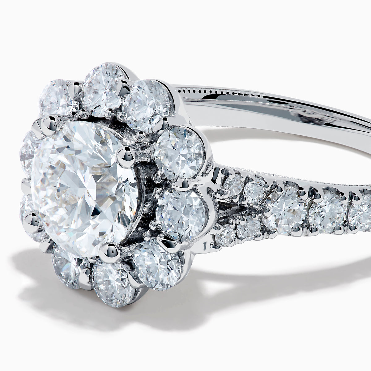 The Star Lab Grown Diamond Fleur Ring in 18K White Gold showcases a large round center lab diamond, with a sparkling halo of smaller diamonds and extra diamonds set along the band.