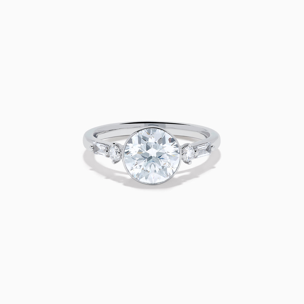 The Star Lab Grown Diamond Moderne Ring in 18K White Gold showcases a large round center diamond with two smaller diamonds on each side, set on a sleek, polished band against a white background.