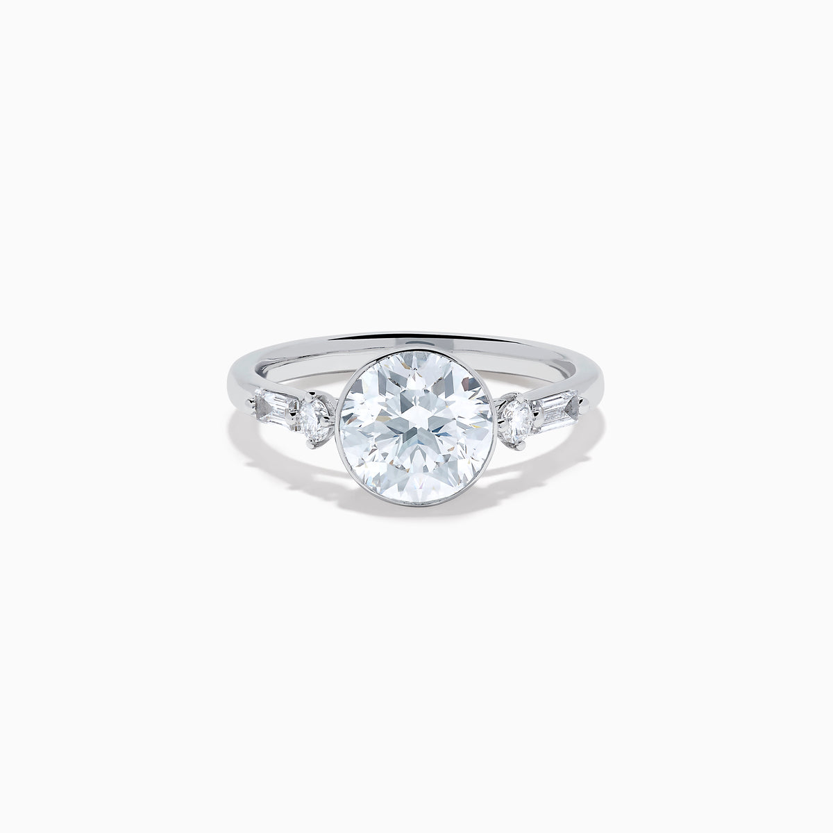 The Star Lab Grown Diamond Moderne Ring in 18K White Gold showcases a large round center diamond with two smaller diamonds on each side, set on a sleek, polished band against a white background.
