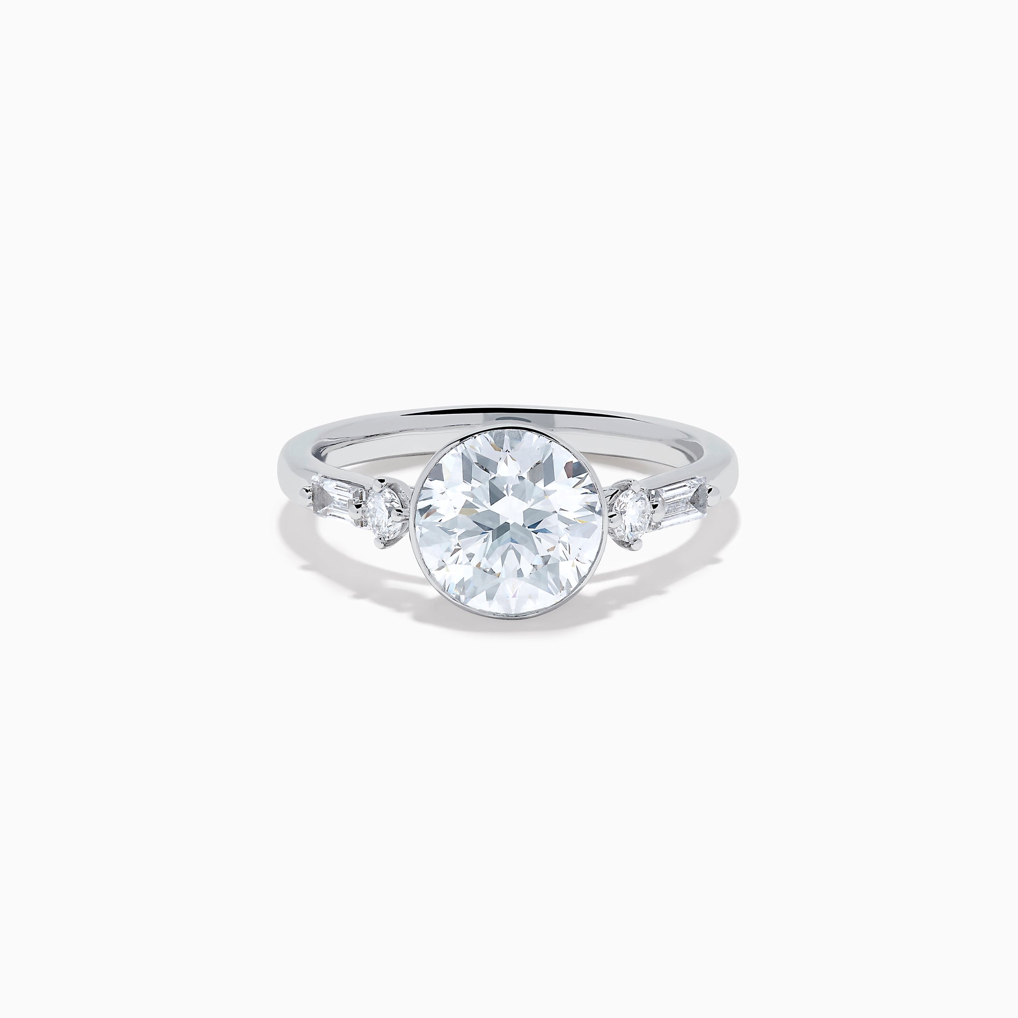 The Star Lab Grown Diamond Moderne Ring in 18K White Gold showcases a large round center diamond with two smaller diamonds on each side, set on a sleek, polished band against a white background.