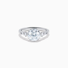The Star Lab Grown Diamond Moderne Ring in 18K White Gold showcases a large round center diamond with two smaller diamonds on each side, set on a sleek, polished band against a white background.
