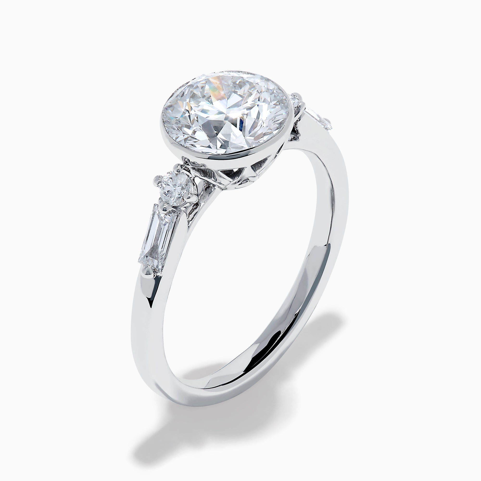 The Star Lab Grown Diamond Moderne Ring in 18K White Gold showcases a large round center diamond with two smaller diamonds on each side, set on a sleek, polished band against a white background.