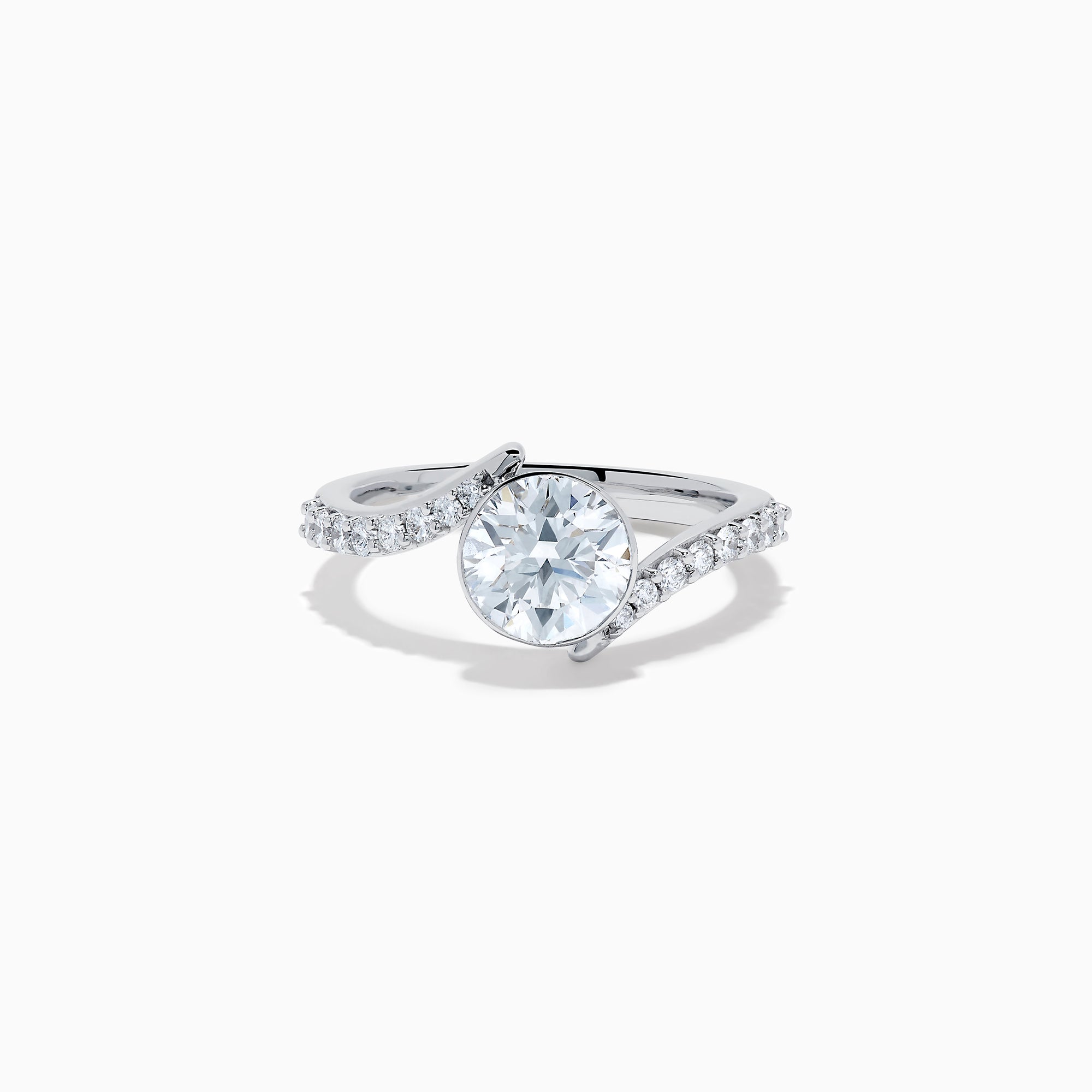 The Star Lab Grown Diamond Connect Ring in 18K White Gold showcases a striking round center stone, with an elegantly twisting band highlighted by sparkling side diamonds for extra brilliance.