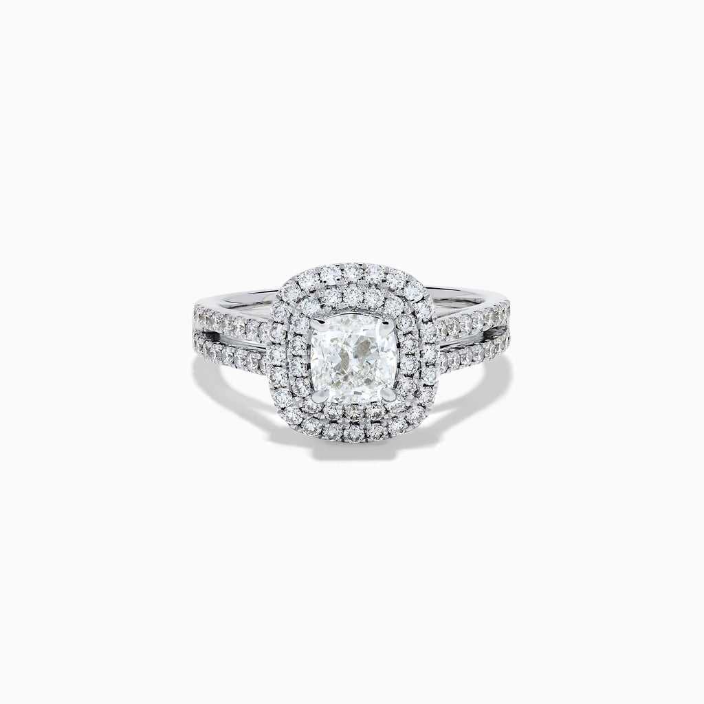 The 18K White Gold Diamond Double Halo Ring showcases a cushion-cut center diamond, surrounded by a double halo and accented with diamonds along the elegant split shank band.