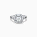 The 18K White Gold Diamond Double Halo Ring showcases a cushion-cut center diamond, surrounded by a double halo and accented with diamonds along the elegant split shank band.