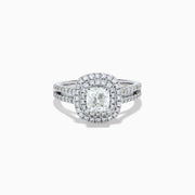 The 18K White Gold Diamond Double Halo Ring showcases a cushion-cut center diamond, surrounded by a double halo and accented with diamonds along the elegant split shank band.