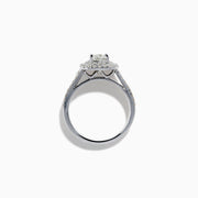 The 18K White Gold Diamond Double Halo Ring showcases a cushion-cut center diamond, surrounded by a double halo and accented with diamonds along the elegant split shank band.