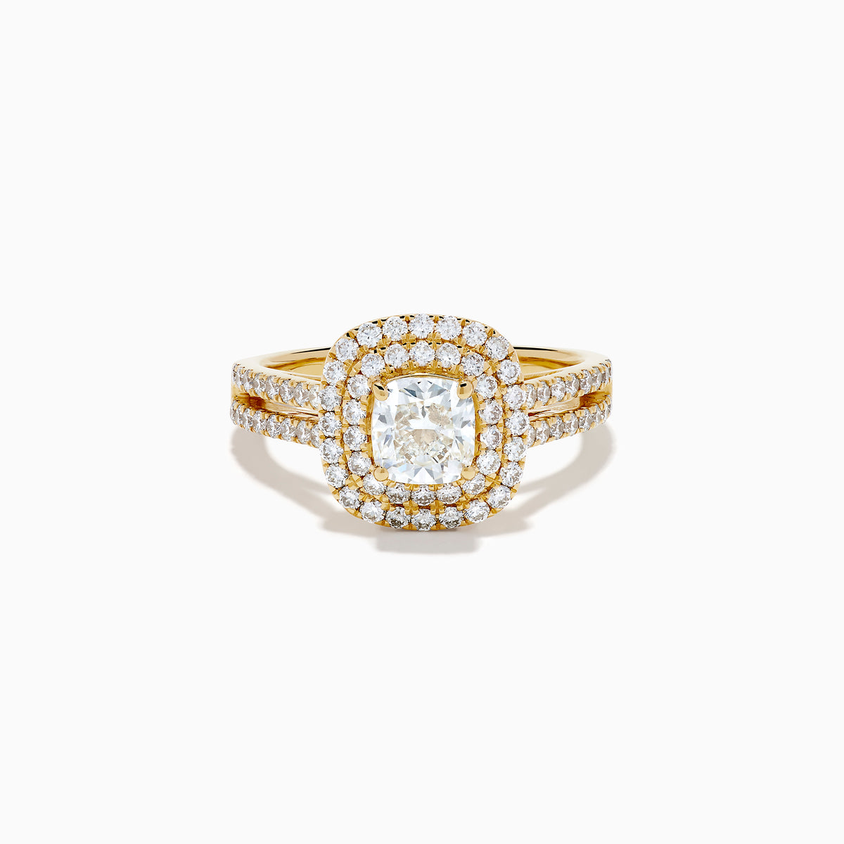 The 18K Yellow Gold Diamond Double Halo Ring showcases a cushion-cut center stone, surrounded by a double halo of round diamonds and additional diamonds set along the split shank band.
