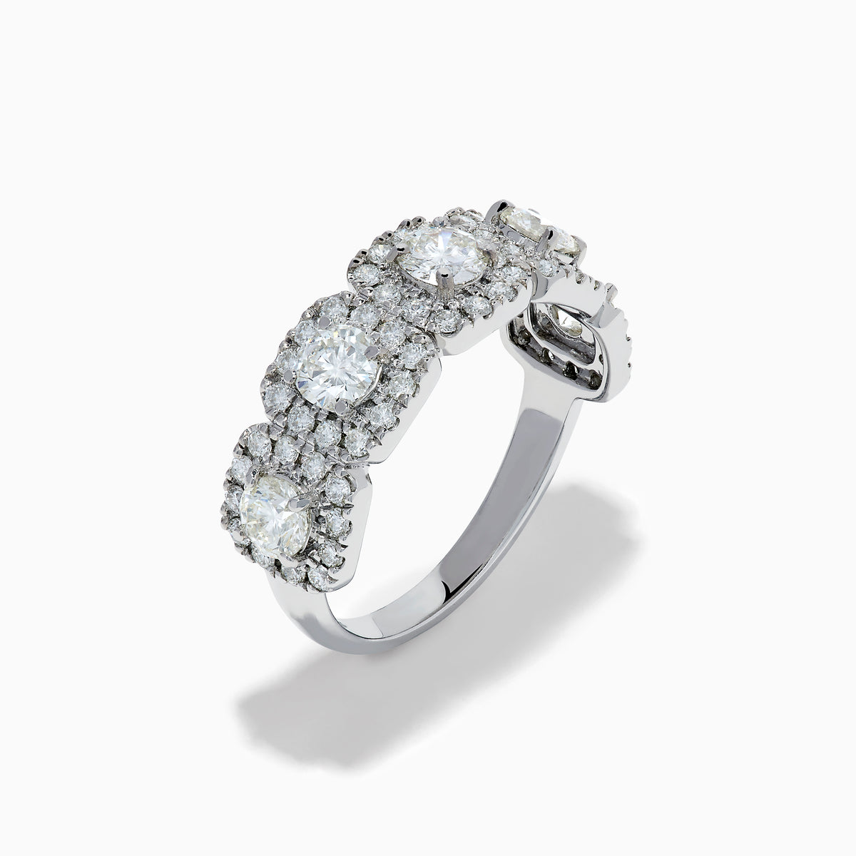 The 18K White Gold Diamond Round Halo Band Ring showcases three central round diamonds, each with a diamond halo, and features rectangular diamond accents on the sides for added brilliance.