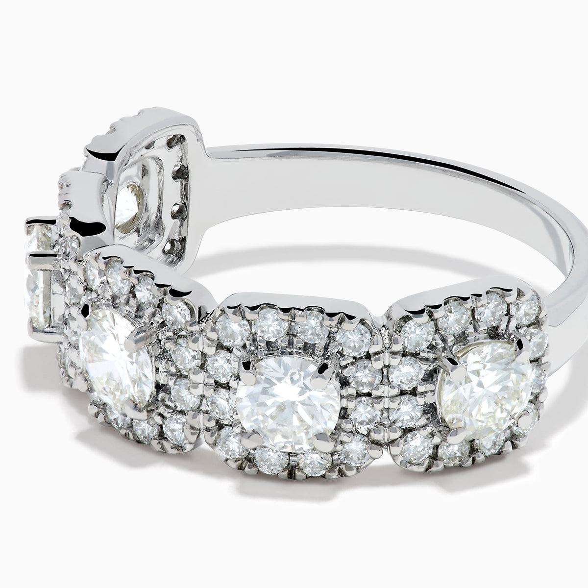 The 18K White Gold Diamond Round Halo Band Ring showcases three central round diamonds, each with a diamond halo, and features rectangular diamond accents on the sides for added brilliance.