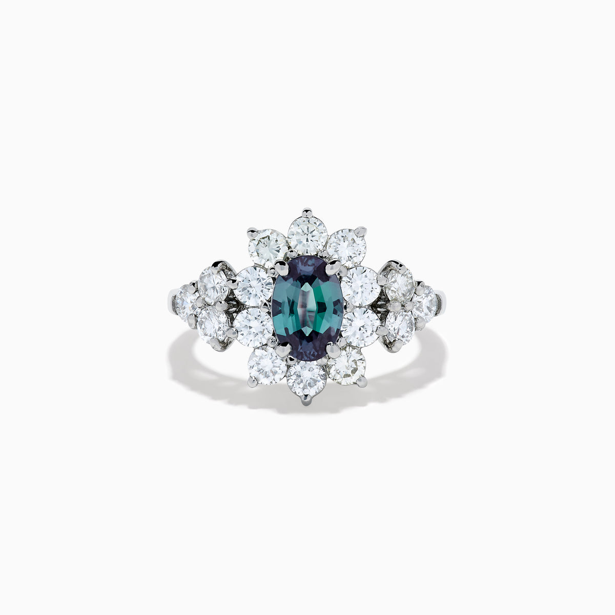 A Platinum GIA Certified Alexandrite and Diamond Starburst Halo Ring, featuring an oval dark blue-green central Alexandrite and sparkling diamond accents, displayed on a white background.