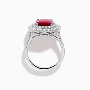 The 18K White Gold Ruby and Diamond Double Halo Ring features an oval ruby encircled by two rows of round white diamonds, set in a sleek 18K white gold band and displayed on a white background.