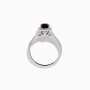 The 18K White Gold GIA Certified Alexandrite and Diamond Ring showcases a cushion-cut Alexandrite surrounded by white diamonds. Its split band is adorned with diamonds, adding elegance, and the ring is displayed against a plain white background.