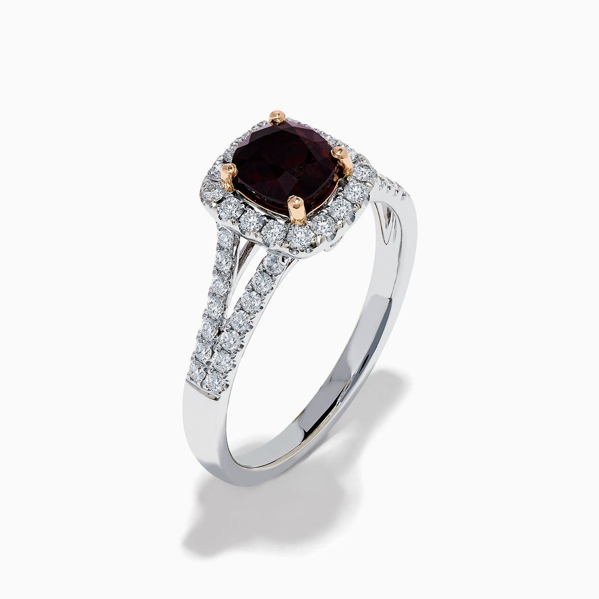 The 18K White Gold GIA Certified Alexandrite and Diamond Ring showcases a cushion-cut Alexandrite surrounded by white diamonds. Its split band is adorned with diamonds, adding elegance, and the ring is displayed against a plain white background.