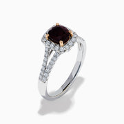 The 18K White Gold GIA Certified Alexandrite and Diamond Ring showcases a cushion-cut Alexandrite surrounded by white diamonds. Its split band is adorned with diamonds, adding elegance, and the ring is displayed against a plain white background.