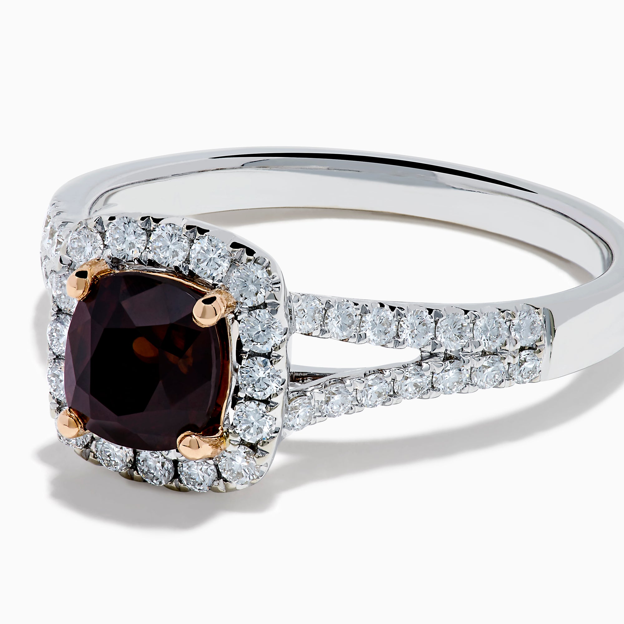The 18K White Gold GIA Certified Alexandrite and Diamond Ring showcases a cushion-cut Alexandrite surrounded by white diamonds. Its split band is adorned with diamonds, adding elegance, and the ring is displayed against a plain white background.