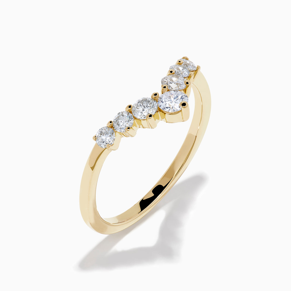 The D’Oro 14K Yellow Gold Diamond Curved Wedding Band features a chevron design with seven round white diamonds of varying sizes set along the pointed curve, shown against a white background.