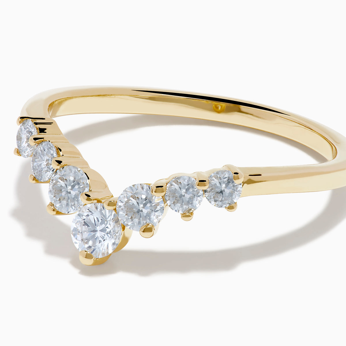 The D’Oro 14K Yellow Gold Diamond Curved Wedding Band features a chevron design with seven round white diamonds of varying sizes set along the pointed curve, shown against a white background.