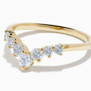 The D’Oro 14K Yellow Gold Diamond Curved Wedding Band features a chevron design with seven round white diamonds of varying sizes set along the pointed curve, shown against a white background.