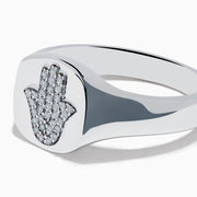 The 925 Sterling Silver Diamond Hamsa Ring features a round face adorned with small clear stones, giving it a sparkling finish.