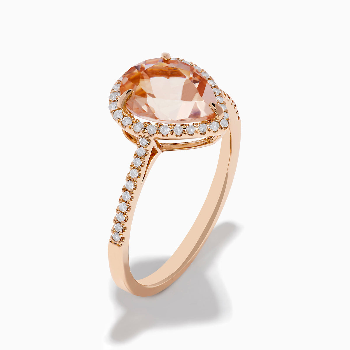 The Blush 14K Rose Gold Morganite and Diamond Ring features a large pear-shaped morganite framed by a halo of sparkling diamonds, with additional diamonds set along the band for added brilliance.