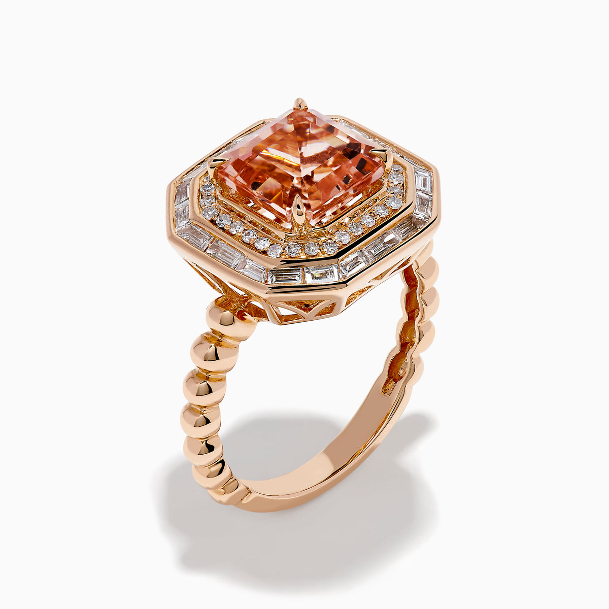 The 14K Rose Gold Morganite and Diamond Geometric Cocktail Ring showcases a large square peach morganite center, framed by two rows of sparkling white diamonds in a geometric halo, set against a white background.