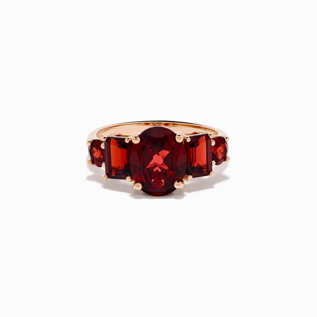 The 14K Rose Gold Multi Shape Garnet and Diamond Hidden Halo Ring showcases a central oval deep red garnet, accented by smaller rectangular and oval garnets on each side, all set in polished rose gold.