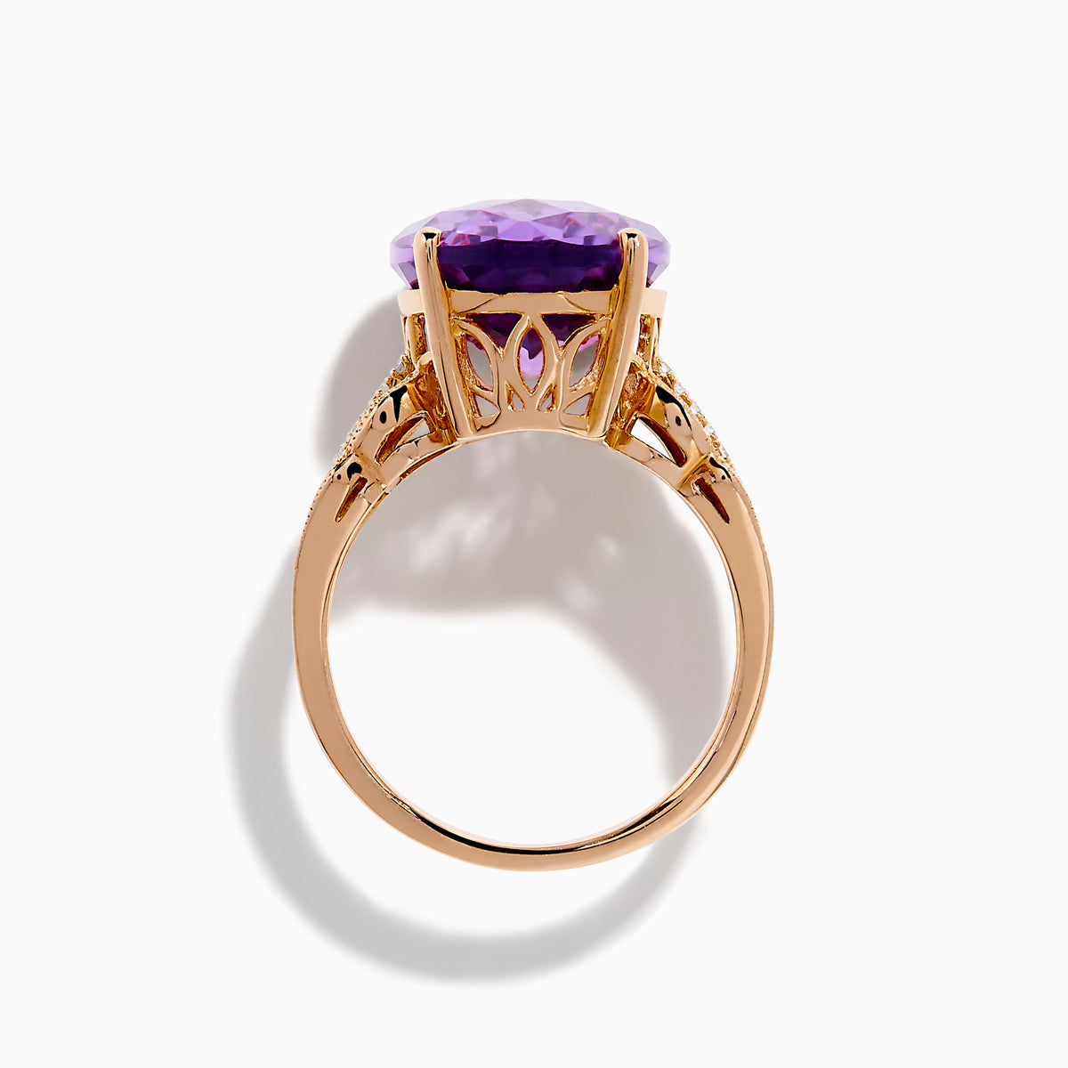 The 14K Rose Gold Purple Amethyst and Diamond Cocktail Ring features a large oval purple amethyst center, accented by three rows of small rectangular diamonds on each side, set in rose gold.