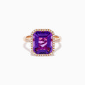 The 14K Rose Gold Amethyst and Diamond Halo Ring features a large, emerald-cut purple amethyst at the center, encircled by sparkling diamonds, and is showcased on a plain white background.