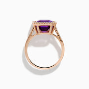 The 14K Rose Gold Amethyst and Diamond Halo Ring features a large, emerald-cut purple amethyst at the center, encircled by sparkling diamonds, and is showcased on a plain white background.