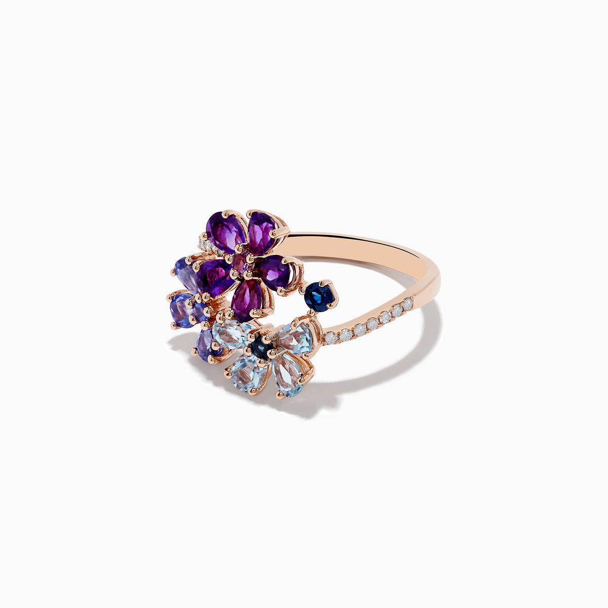 A 14K Gold Blue Topaz, Amethyst, Tanzanite, Sapphire and Diamond Ring featuring two floral designs with purple, blue, and light blue gemstones on a band adorned with small diamonds, set against a plain white background.