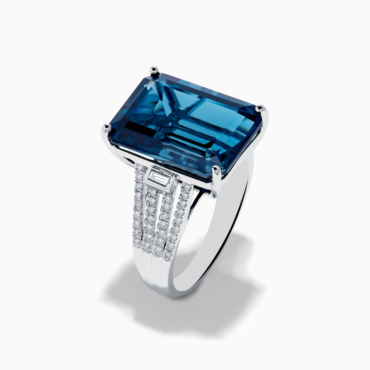 The Ocean Bleu 14K White Gold London Blue Topaz and Diamond Cocktail Ring showcases a large emerald-cut blue topaz set with four prongs, accented by sparkling diamonds along the band.
