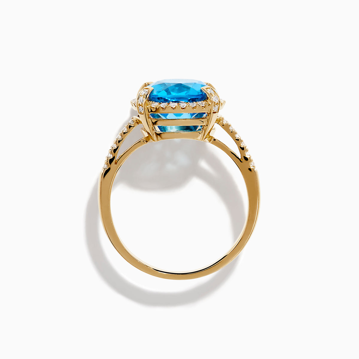 The Ocean Bleu 14K Yellow Gold Blue Topaz Ring showcases a large oval center blue topaz, embraced by a diamond halo and additional diamonds adorning the band.