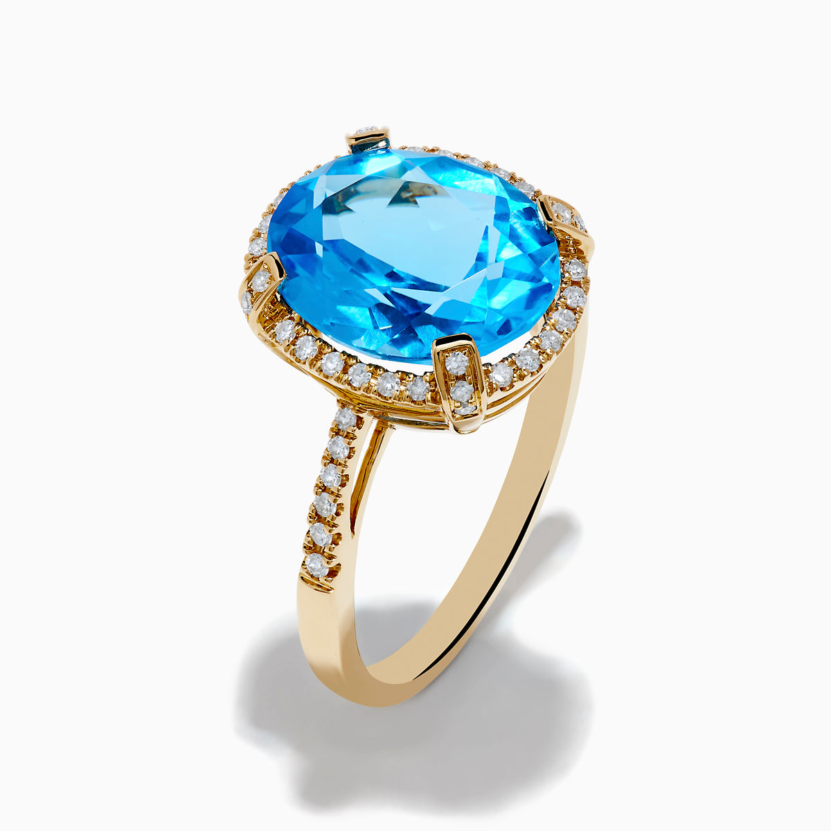 The Ocean Bleu 14K Yellow Gold Blue Topaz Ring showcases a large oval center blue topaz, embraced by a diamond halo and additional diamonds adorning the band.