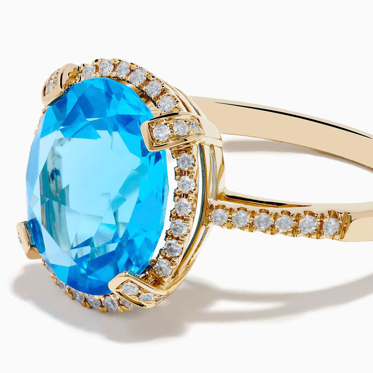 The Ocean Bleu 14K Yellow Gold Blue Topaz Ring showcases a large oval center blue topaz, embraced by a diamond halo and additional diamonds adorning the band.