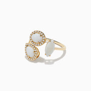 The Aurora 14K Yellow Gold Opal and Diamond Ring features three white gems—two oval and teardrop-shaped stones with diamond halos, plus a sideways marquise-cut opal—displayed on a white background.