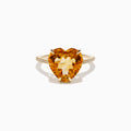 The Sunset 14K Yellow Gold Citrine and Diamond Heart Ring features a large heart-shaped citrine gemstone at the center, accented by small diamonds on the band, and is pictured against a white background.