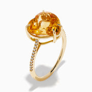 The Sunset 14K Yellow Gold Citrine and Diamond Heart Ring features a large heart-shaped citrine gemstone at the center, accented by small diamonds on the band, and is pictured against a white background.
