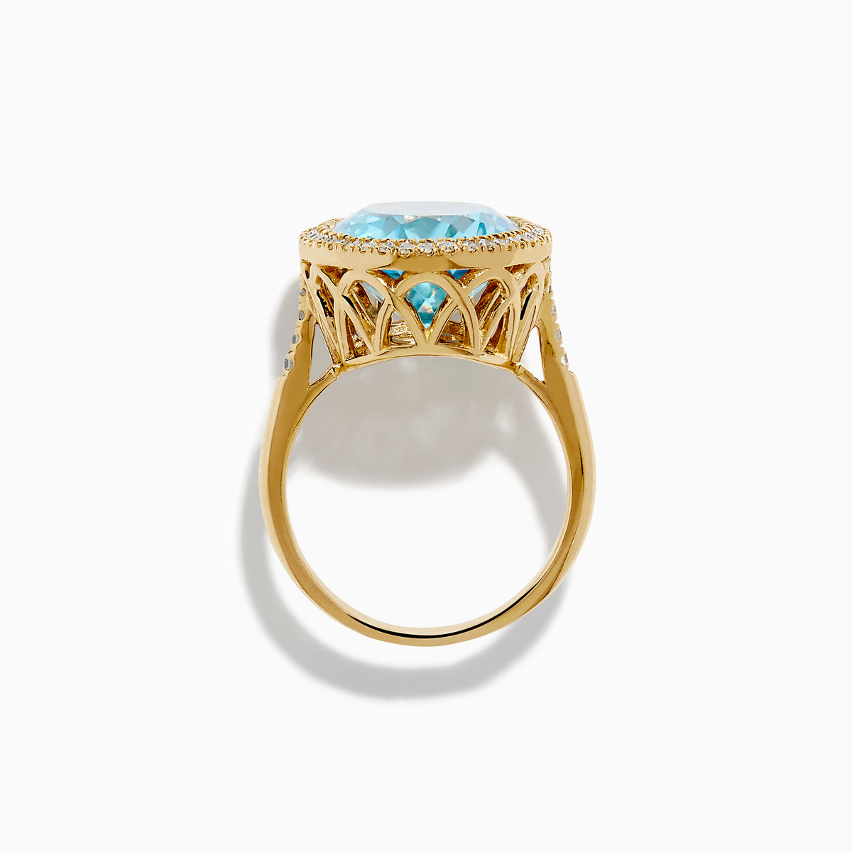 The 14K Yellow Gold Blue Topaz and Diamond Halo Cocktail Ring showcases a large oval blue topaz gemstone surrounded by sparkling diamonds, presented against a simple white background.