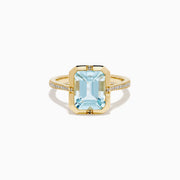 The 14K Yellow Gold Aquamarine and Diamond Bezel Solitaire Ring showcases an emerald-cut light blue aquamarine center stone with diamond accents on the band, displayed against a white background.