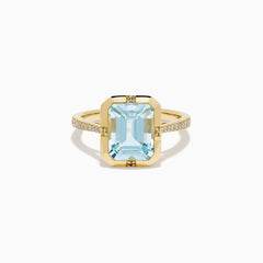 The 14K Yellow Gold Aquamarine and Diamond Bezel Solitaire Ring showcases an emerald-cut light blue aquamarine center stone with diamond accents on the band, displayed against a white background.
