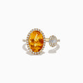 The Sunset 14K Yellow Gold Citrine and Diamond Ring features a large oval citrine framed by diamonds and a smaller baguette diamond cluster, both set on a slim yellow gold band against a white background.